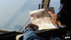 A Vietnamese Air Force crew member checks a map while searching for the missing Malaysia Airlines flight off Vietnam's island Phu Quoc on March 11, 2014. 