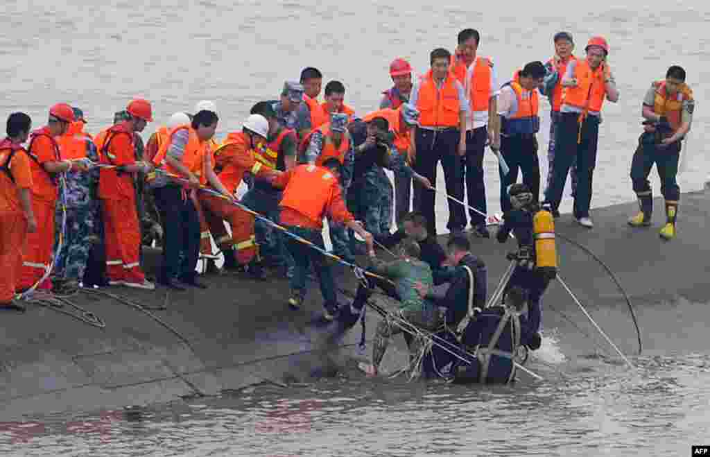 Une femme de 65 ans, au centre, secourue par des plongeurs du navire Dongfangzhixing (&quot;Etoile de l&#39;Orient&quot;) qui a fait naufrage dans le fleuve Yangtsé à Jianli, dans la province Hubei, Chine le 2 juin 2015