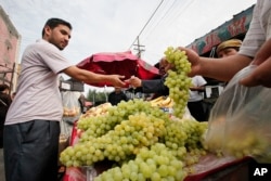 A Uighur man buys grapes at a street stall in Urumqi, western China's Xinjiang region, Monday, July 13, 2009.