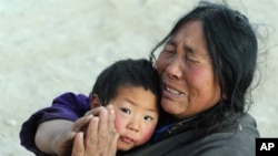 Quake survivor Sonammon, 52, who lost ten members of her family from the recent earthquake, gestures in prayer while holding onto her nephew in Jiegu, Yushu County, on April 16, 2010. The death toll from the strong earthquake in northwestern China has ris
