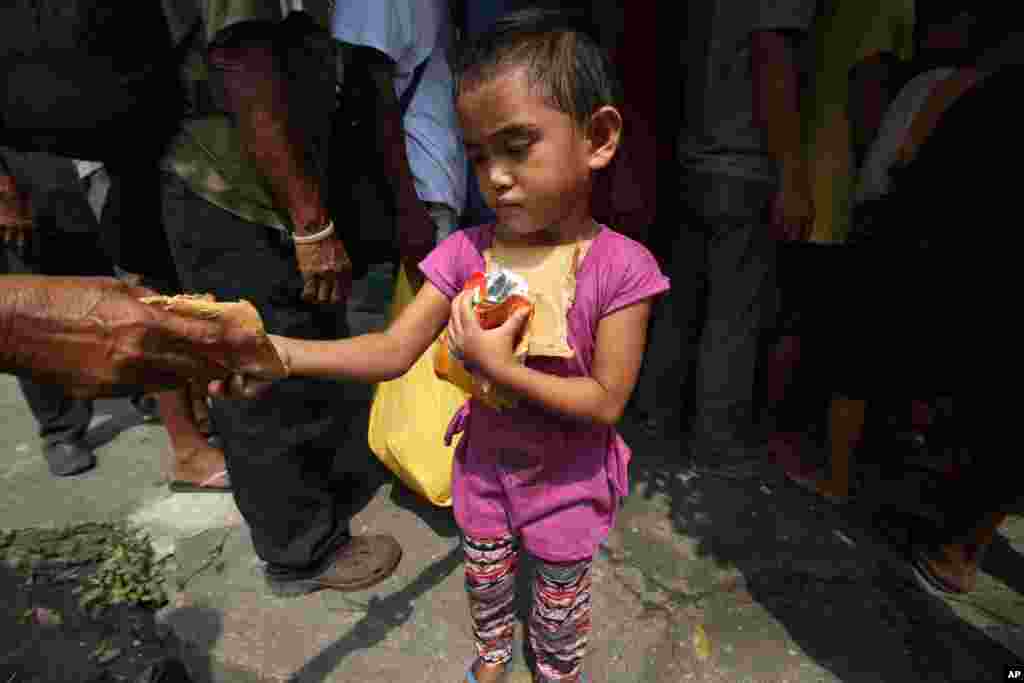 Seorang anak perempuan Filipina dari keluarga miskin&nbsp;menerima bantuan roti dan minuman di&nbsp;Manila. 