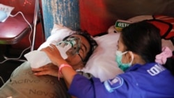 A woman adjusts a non-rebreather mask for her 59-year-old father who is suffering from coronavirus disease (COVID-19) at a temporary tent outside the emergency ward of a government hospital in Bekasi, on the outskirts of Jakarta, Indonesia, June 25, 2021.