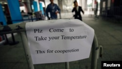 A sign requesting people to come have their temperature taken is seen at the entrance to the Canton Fair in Guangzhou, Guangdong province.