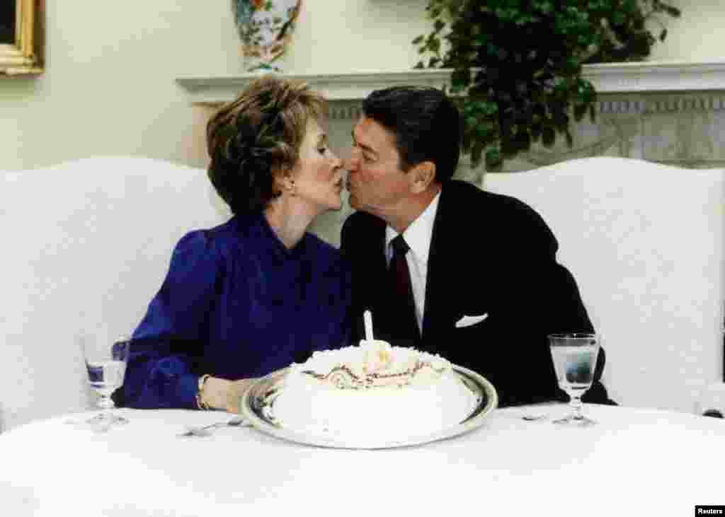 President Ronald Reagan and his wife Nancy kiss on their wedding anniversary in the White House, March 4, 1985.
