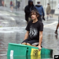 A boy floats on a newspaper box in a flooded street in the Soho section of Manhattan after Hurricane Irene passed over the New York City area August 28, 2011