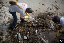 FILE - Health agents remove plastic bottles during an operation to eradicate the Aedes aegypti mosquito in Niteroi, Brazil, March 8, 2016.