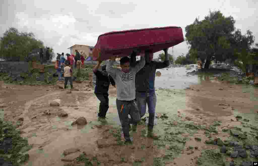 Men carry a mattress they salvaged from a flooded home in Tiquipaya near Cochabamba, Bolivia, Thursday, Feb. 8, 2018.
