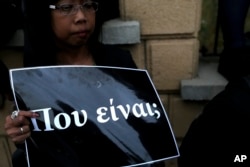 A woman holds a banner in Greek reading "Where are they" outside the presidential palace in Nicosia, Cyprus, April 26, 2019.