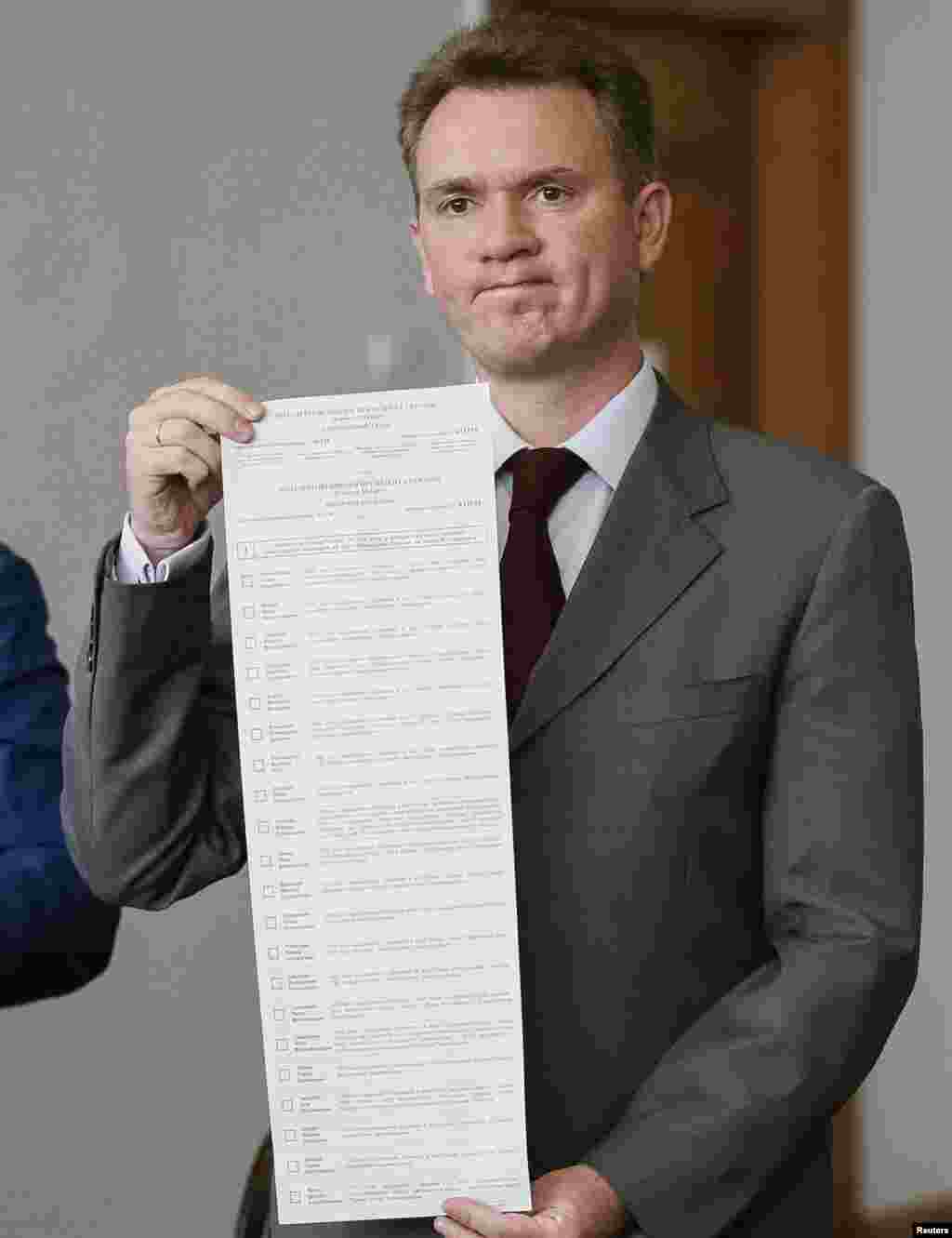 Mykhaylo Okhendovsky, head of Ukraine&#39;s Central Election Commission, shows a long ballot with names of 21 presidential candidates, at a news conference, in Kyiv, May 14, 2014.