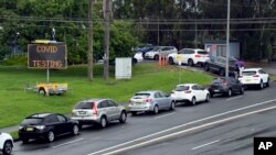 FILE - People line up in cars for COVID-19 tests at a clinic in Sydney, Wednesday, Dec. 29, 2021.