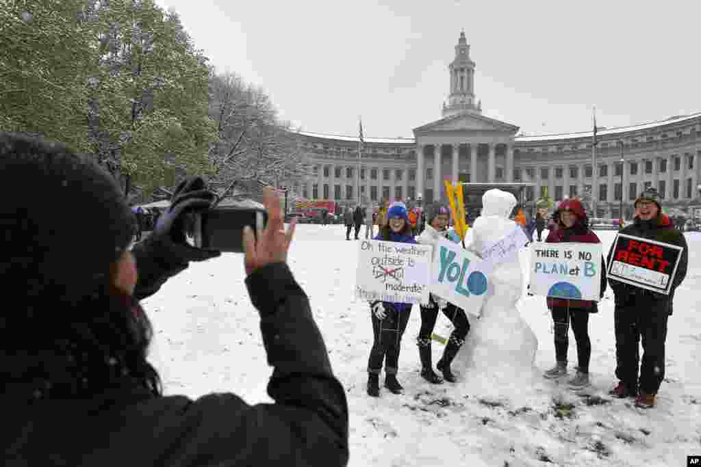 Dori Mann takes a snapshot of friends and family posing with a snowman draped with an anti-Trump sign as they all participated in a climate change awareness march and rally, in Denver, April 29, 2017. 