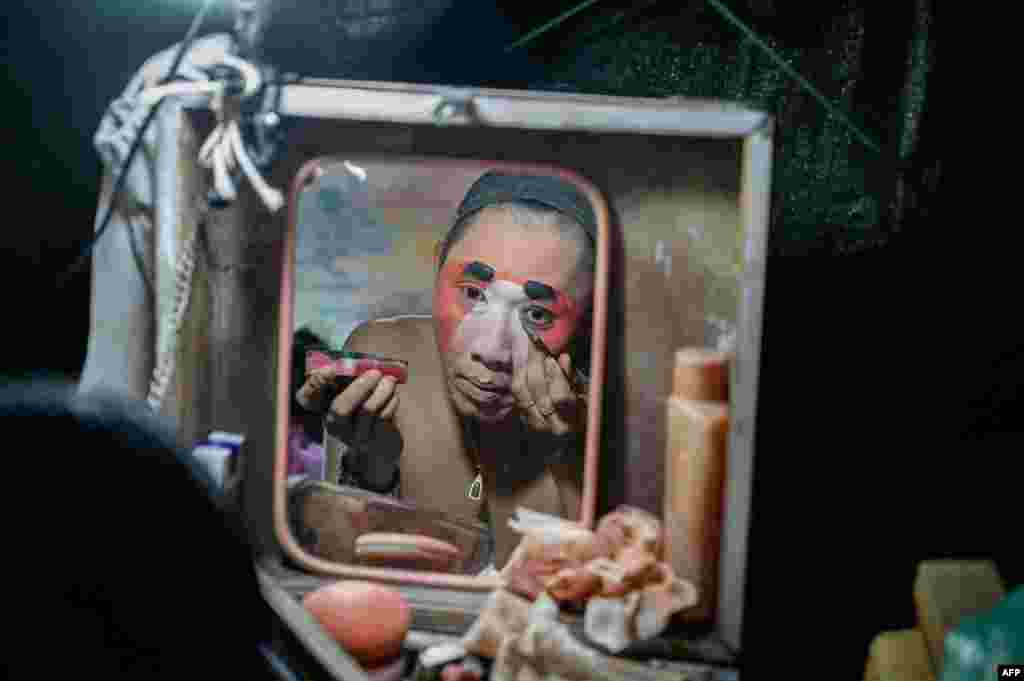 A reflection of an actor applying makeup is seen in the mirror before a Chinese opera performance by Thailand&#39;s Sai Bo Hong troupe at a makeshift stage on a street festival in Bangkok, Dec. 28, 2019.