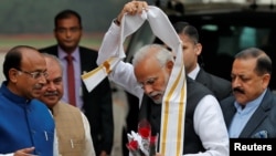 India's Prime Minister Narendra Modi removes a stole given to him by a minister upon his arrival at the Parliament on the first day of the winter session in New Delhi, India, Dec. 11, 2018. 
