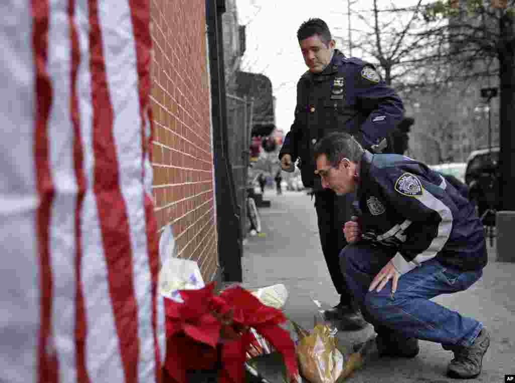 미국 뉴욕 브룩클린에서 흑인 20대가 경관 2 명을 총으로 살해한 후 자살한 사건이 발생한 가운데, 현장 주변에서 다른 경관들이 숨진 경관등을 추모하는 꽃다발을 놓고 있다.