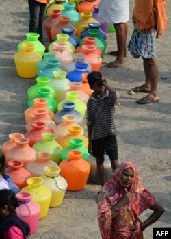 Indian residents queue with plastic containers to get drinking water from a tanker in the outskirts of Chennai, May 29, 2019. An unrelenting heat wave triggered warnings of water shortages and heatstroke in India on June 1.