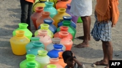 Indian residents queue with plastic containers to get drinking water from a tanker in the outskirts of Chennai, May 29, 2019. 