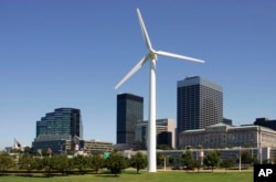 FILE - A small wind turbine rises in front of the downtown skyline at the Great Lakes Science Center in Cleveland.