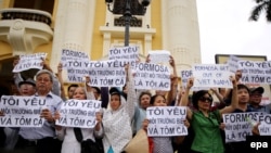 FILE - Vietnamese protesters hold banners reading "Get out Formosa" and "I love the sea, shrimp and fish" during a rally denouncing recent mass fish deaths in Vietnam's central province, in Hanoi, Vietnam, May 1, 2016.