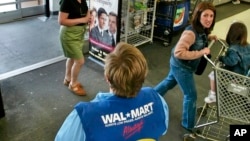 FILE - A store greeter offers help to shoppers at a Walmart store in West Norriton, Pa.