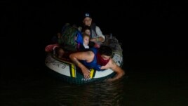 A human trafficker takes migrants, mostly from Central American countries, on a small inflatable raft towards U.S. soil in Roma, Texas Tuesday, March 30, 2021.