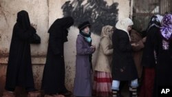 FILE - Syrian women queue for hours to buy bread at a bakery.