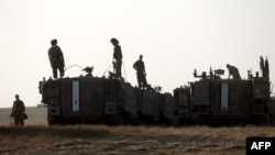 Israeli soldiers stand on their armoured personnel carrier (APC) in an army deployment area near the border with the Gaza Strip, July 6, 2014.