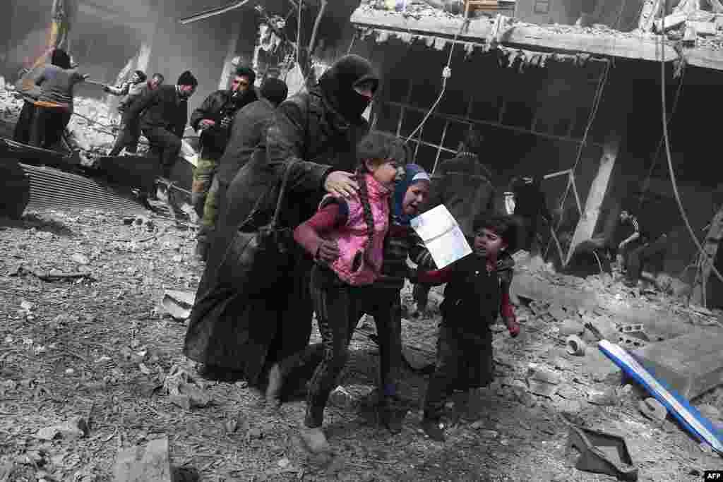 A Syrian woman and children run for cover following government bombing in the rebel-held town of Hamouria, in the besieged Eastern Ghouta region on the outskirts of the capital Damascus. Heavy Syrian bombardment killed 44 civilians in rebel-held Eastern Ghouta.