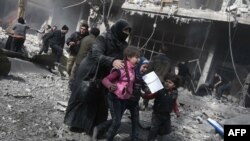 Une femme et des enfants courent se mettre à l'abri après les bombardements des forces gouvernementales dans la ville rebelle de Hamouria, dans la région de la Ghouta orientale en Syrie, le 19 février 2018.
