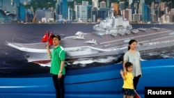 参观者在香港中国海军基地一副反映辽宁号航母的背景画面前拍照留影。（2017年7月8日）