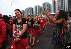 Members of Canada's Olympic team parade past dancers following a flag-raising ceremony at the Athletes Village in Rio de Janeiro, Brazil on Aug. 2, 2016.