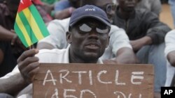 An opposition protestor holds a sign reading 'Faure, Resign,' referring to Togo's president, Faure Gnassingbe, and citing an article of the constitution that protesters say gives them the right to engage in civil disobedience, Aug. 25, 2012.