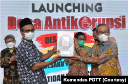 Kepala Desa Panggungharjo, Bantul, DI Yogyakarta, Wahyudi Anggoro Hadi menerima plakat dari Ketua KPK Alexander Marwata. (Foto: Courtesy/Kemendes PDTT)