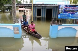 Men paddle their boat through the lawns of a partially submerged church at Kuttanad in Alleppey district in the southern state of Kerala, India, Aug. 24, 2018.