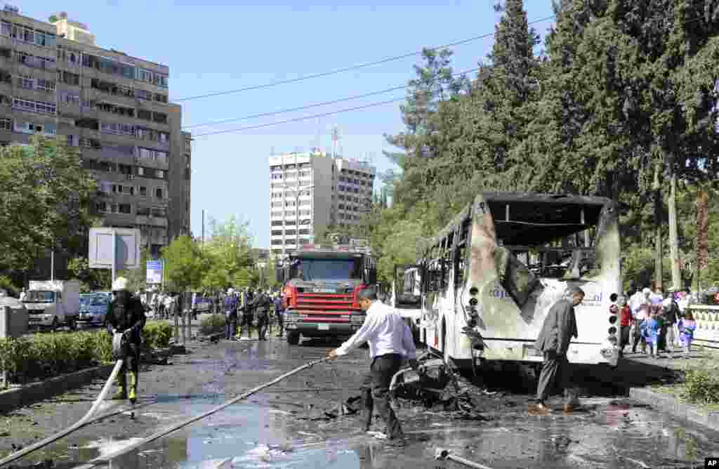 This photo released by the Syrian official news agency SANA, shows Syrian fire fighters extinguishing burning cars after a car bomb exploded near the prime minister's convoy in Mazzeh, Damascus, April 29, 2013.