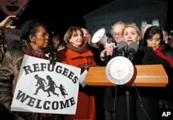 Farah Amer Kamal, from Iraq, speaks with Rep. Sheila Jackson Lee, D-Texas, left, House Minority Leader Nancy Pelosi of California, and Senate Minority Leader Chuck Schumer of New York, and other members of Congress nearby in front of the Supreme Court about President Donald Trump's recent executive orders in Washington, Jan. 30, 2017.