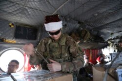 Seorang tentara AS memeriksa hadiah Natal di atas helikopter di Irbil, Irak menuju pangkalan militer AS di Suriah timur, dalam operasi "Holiday Express", Senin, 23 Desember 2019.