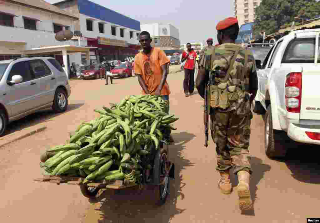 A Central African Republic soldier walks past a vendor on a street in Bangui, December 31, 2012.