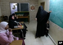 Rawiya Ali, right, a volunteer who teaches illiterate women, gives a class at a community service center marking International Women's Day, in Al Baqa'a Palestinian refugee camp, north of Amman, Jordan, March 8, 2011.