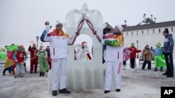 In this photo provided by Olympictorch2014.com torch bearers Riyaz Ibragimov, left, and Lyubov Poryvayeva hold their torches in Sviyazhsk on the Volga River, Russia, Dec. 30, 2013. 