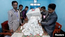 A polling officer pours ballot papers from a box onto a table to count during parliamentary elections in Dhaka, Bangladesh, Jan. 5, 2014. 