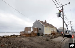A utility worker attaches lines on a power pole, March 6, 2018, in Marshfield, Massachusetts.