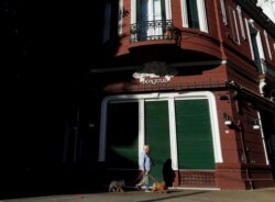 A woman walks her dogs in front of the facade of the Don Julio steakhouse, as the spread of the coronavirus disease (COVID-19) continues, in Buenos Aires, Argentina May 11, 2020. Picture taken May 11, 2020. REUTERS/Agustin Marcarian