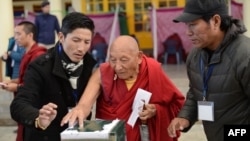 FILE - Palden Gyatso is guided as he casts his vote to elect a sikyong (prime minister) of the Central Tibetan Administration and lawmakers in McLeod Ganj, India, March 20, 2016. The Tibetan monk died Nov. 30, 2018, in Dharamsala, India, at age 85.