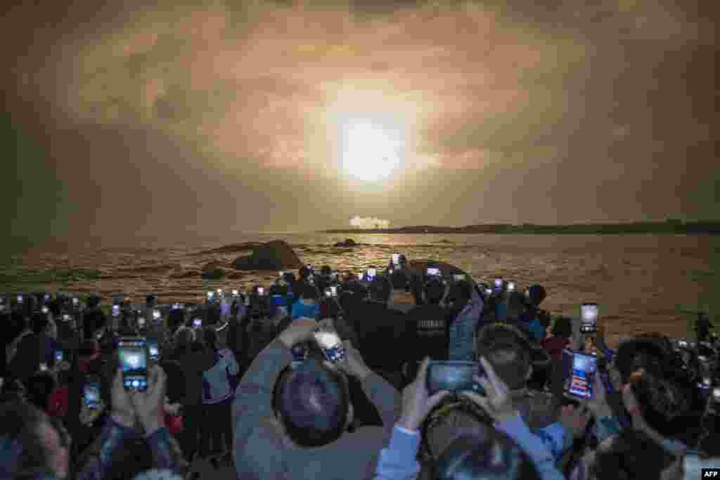People take photos as China&#39;s heavy-lift Long March 5 rocket blasts off from its launch center in Wenchang, south China&#39;s Hainan province.