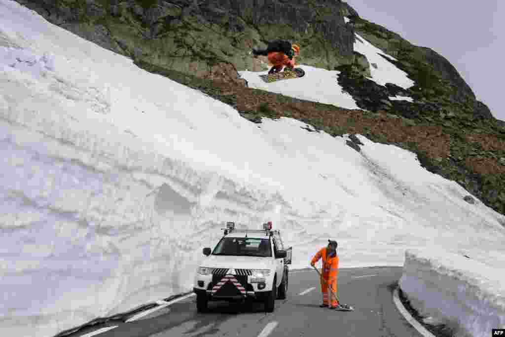 Snowboarder Sebastien Jam jumps above a man on the road of the Grand-Saint-Bernard pass. Connecting Switzerland and Italy, the Grand-Saint-Bernard pass is due to reopen for the summer season with a two week delay on June 14, 2013.