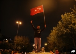 A supporter of Turkey's President Recep Tayyip Erdogan and The Justice and Development Party (AKP), waves a national flag as he celebrates outside the AKP headquarters, in Istanbul, Nov. 1, 2015.