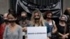 Wearing a gag over her mouth, a woman holds a sign that reads in Portuguese "Down the dictatorship" during an act organized by the NGO Rio de Paz to remember the victims of Brazil's dictatorship, in Rio de Janeiro, Brazil, Dec. 8, 2018. 