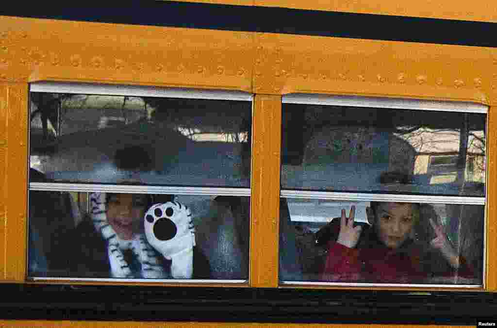 Siswa-siswa Sekolah Dasar Sandy Hook mengintip dari bus sekolah yang membawa mereka ke gedung sekolah yang baru di Monroe, Connecticut.