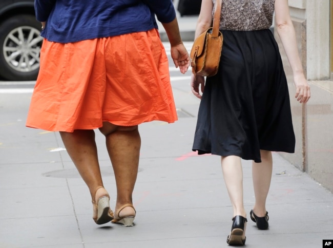 Seorang perempuan dengan masalah berat badan berlebih berjalan di New York, 13 Juli 2015. (Foto: dok)