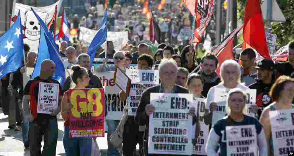 Protesters hold signs and wave flags during a demonstration outside of the security perimeter of the G8 summit in Enniskillen, Northern Ireland, June 17, 2013.